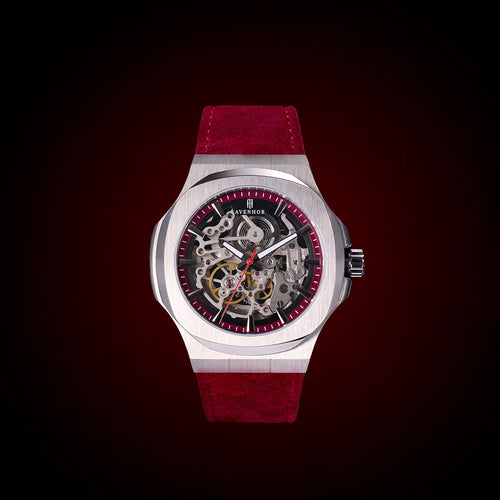 Watch with red strap and visible mechanism on a dark background